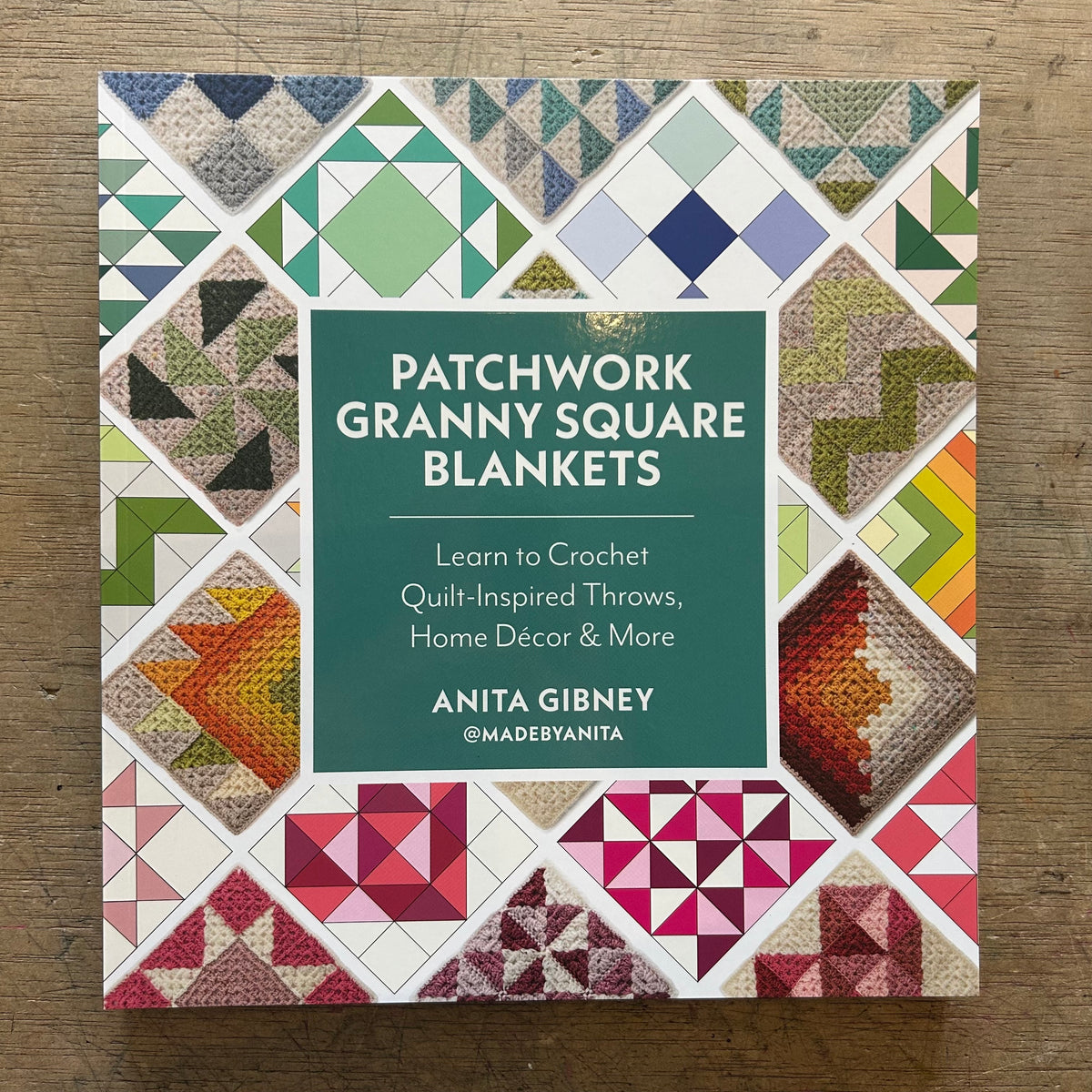 Patchwork Granny Square Blankets book by Anita Gibney, featuring a colorful quilted patchwork cover design with a central dark green title block, photographed on a wooden surface.