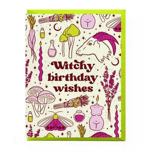 A greeting card with a white background and a colorful witch-themed illustration, featuring the text 'Witchy birthday wishes' in dark red. The card is decorated with drawings of a goat head, mushrooms, a wand, a potion bottle, a broom, a moth, , all in purple, green, and yellow accents.