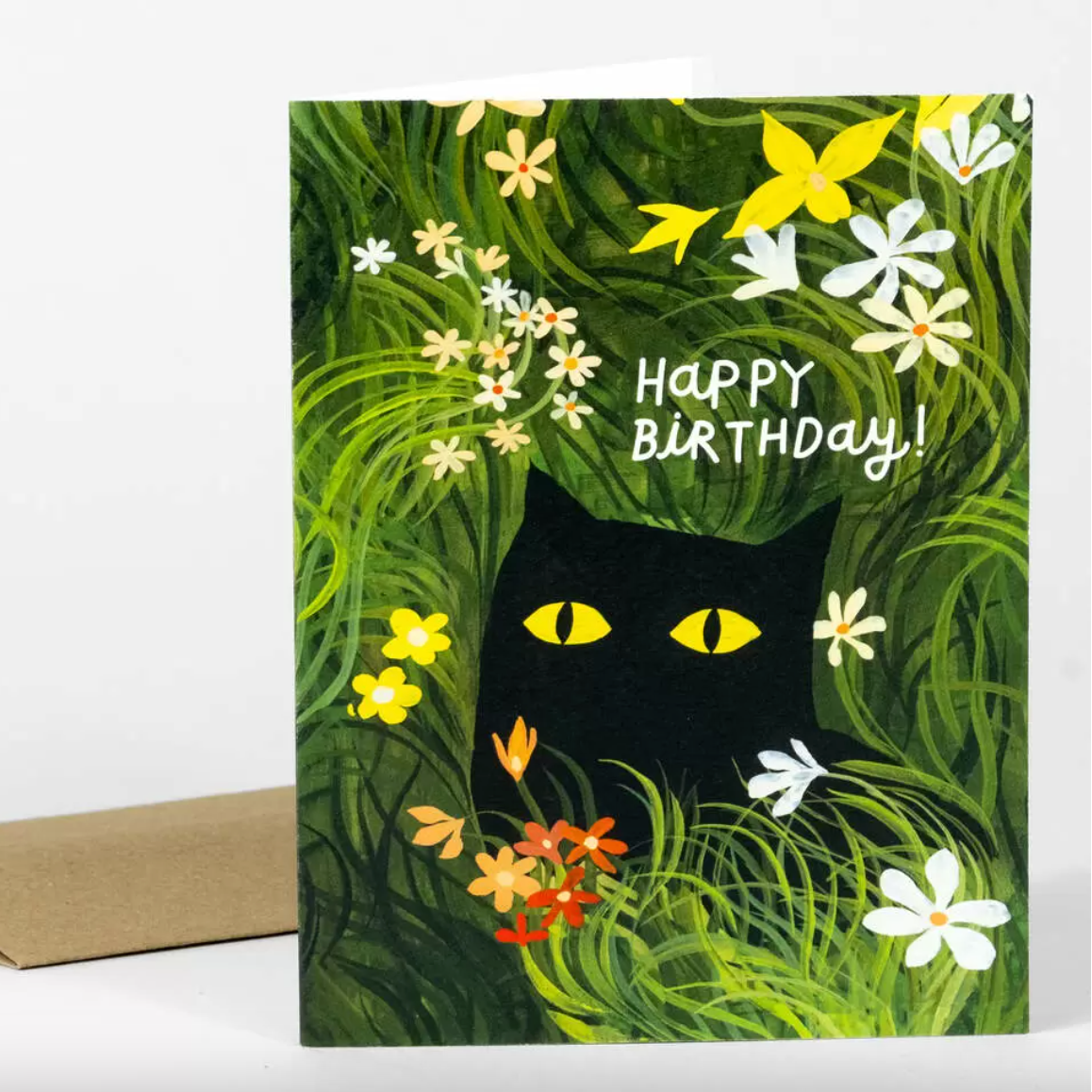 Birthday card with a black cat surrounded by flowers and greenery on a white background