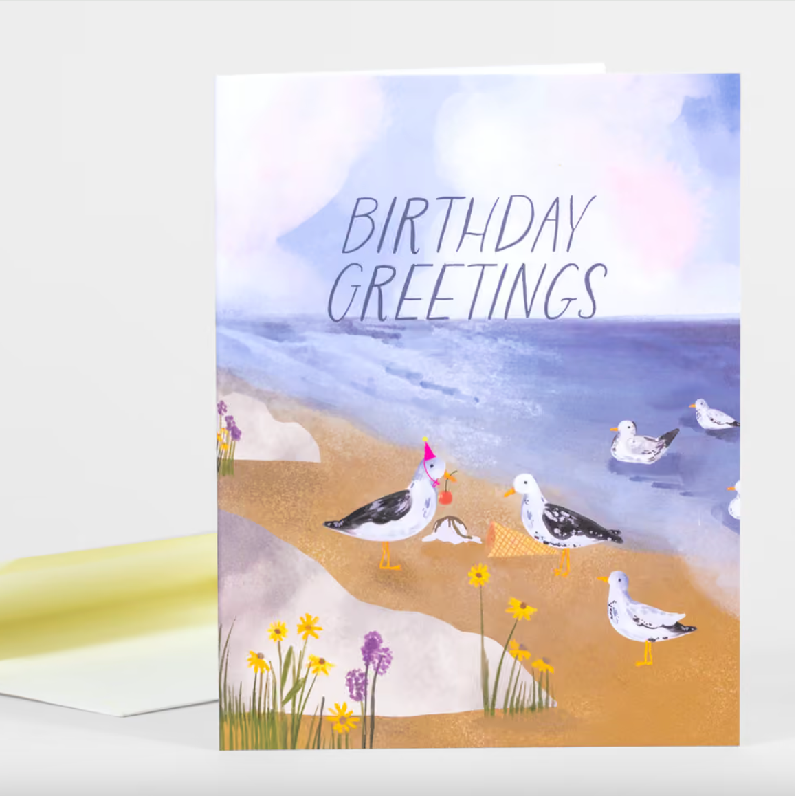 A card illustrated with a beach scene of seagulls gathering around an ice cream cone with one of them wearing a birthday hat and the text "Birthday Greetings" above.