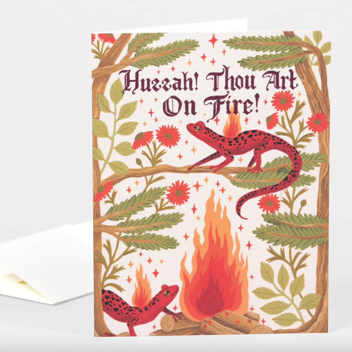 Card featuring two red salamanders by a campfire between two trees and text that reads "Huzzah! Thou art on fire!"