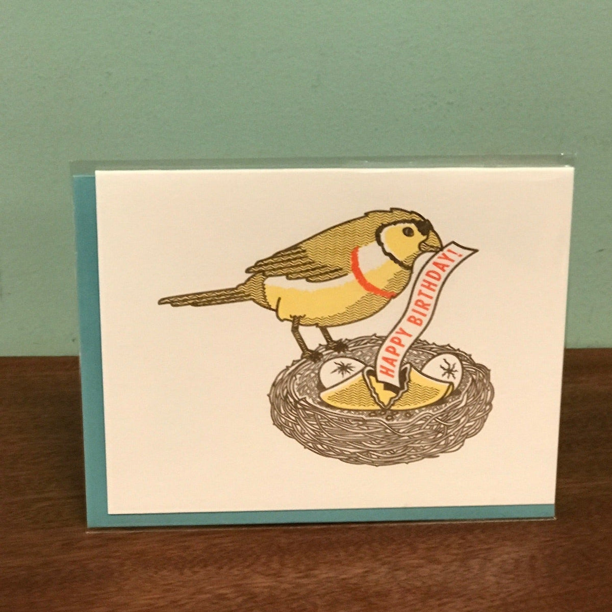 A greeting card with a bird opening a fortune cookie with its beak. The fortune says Happy Birthday.