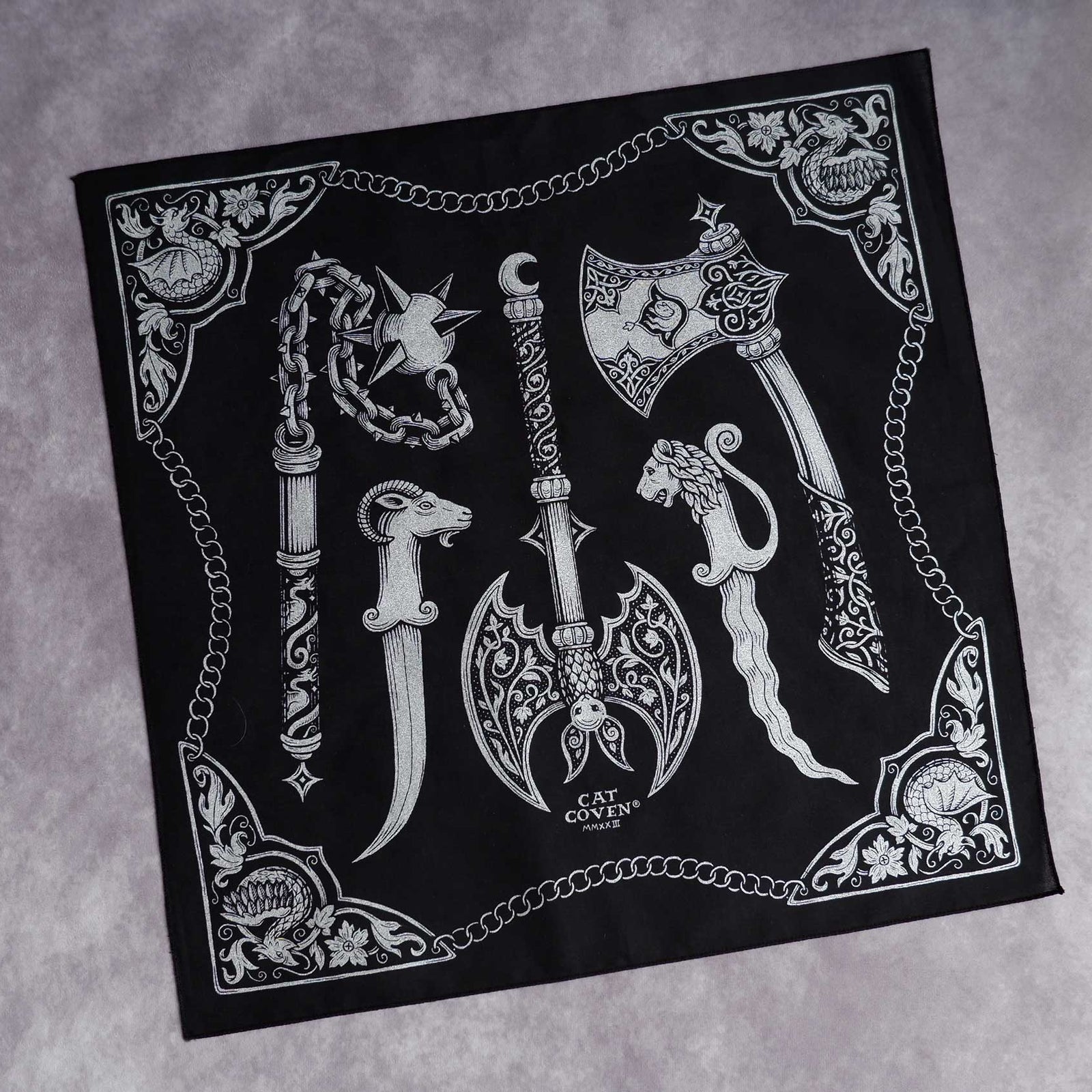 Black bandana with silver weapon designs on a gray background