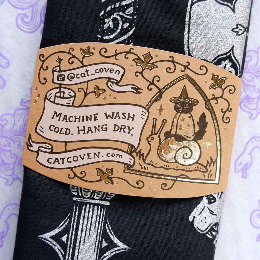 Label on a black fabric with cat-themed design and text