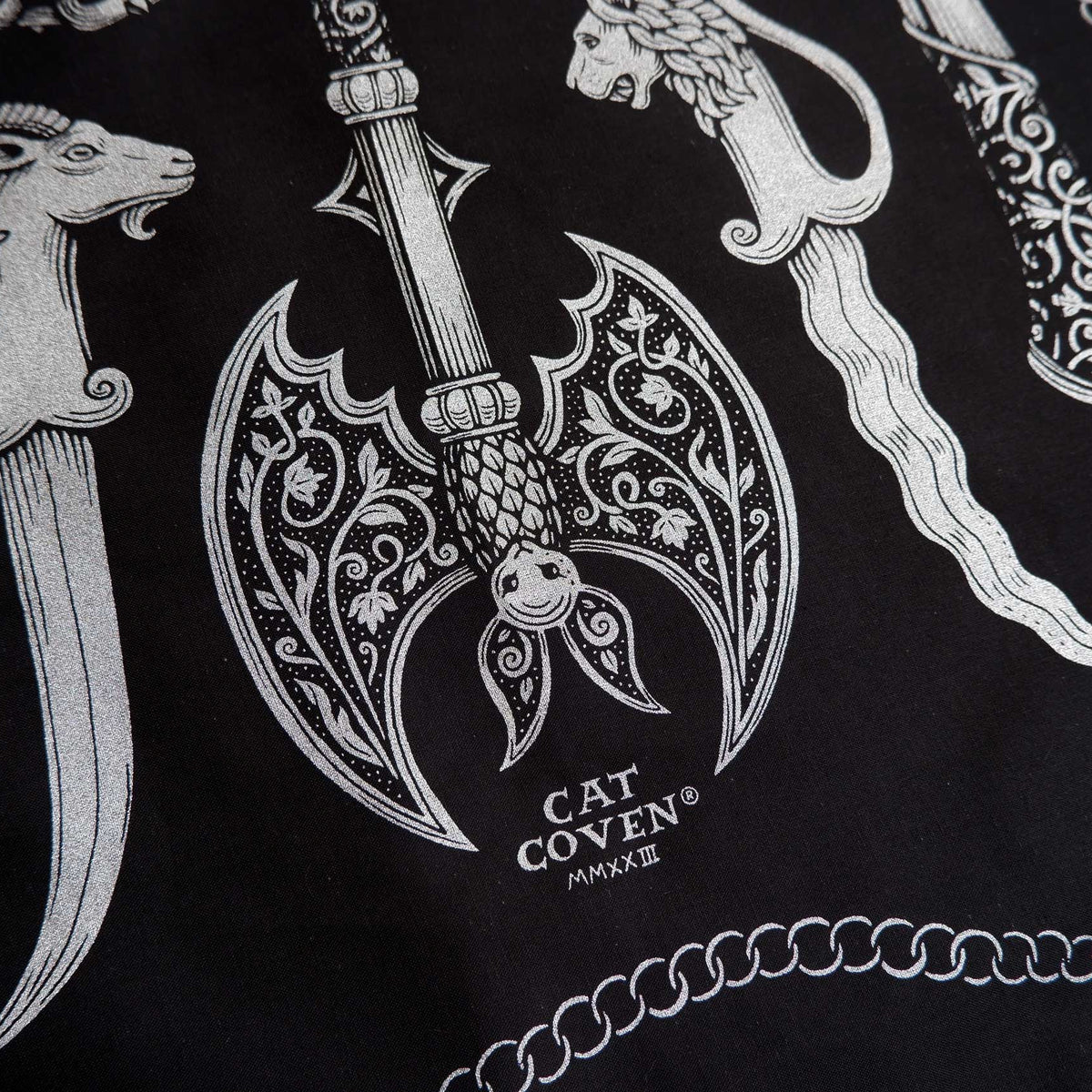 Decorative design on a bandana with a dagger, axe, and other elements on a black background with 'Cat Coven' branding.