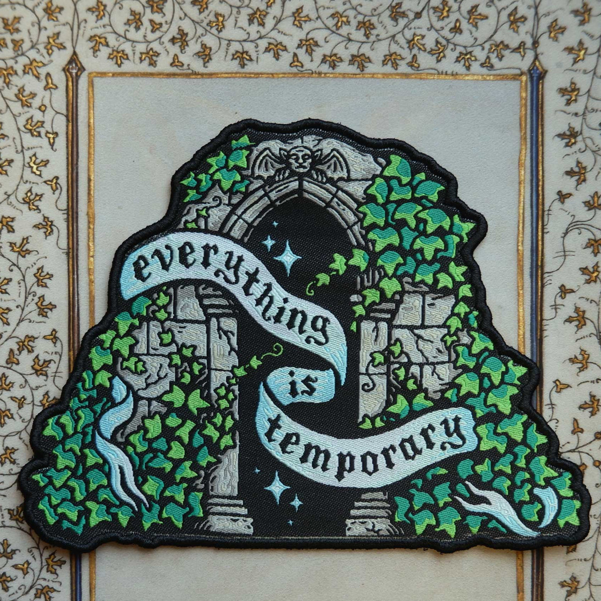 Decorative patch with archway and ivy design and text that says "everything is temporary" on a decorative background