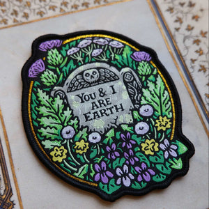 Embroidered patch with tombstone design and floral elements on a decorative background