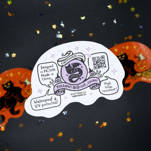 A die-cut white sticker featuring a purple cat illustration and handwritten-style text, placed on a black background with scattered gold and silver confetti. Two orange cat-shaped stickers are partially visible behind it.