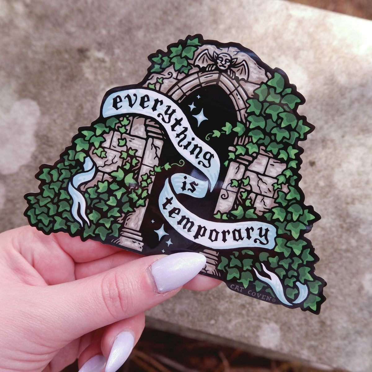 Decorative sticker with ivy design and 'everything is temporary' text held by a hand.