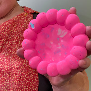 Person holding a pink dish against a neutral background.