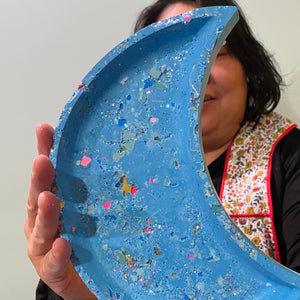 Person holding a blue eco resin crescent moon dish against a plain background.