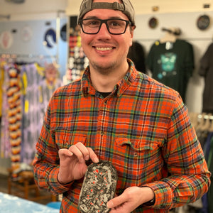 Man holding a tray with a terrazzo pattern in a store setting. 
