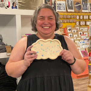 Person holding a tray with colorful terrazzo patterns in a store setting.