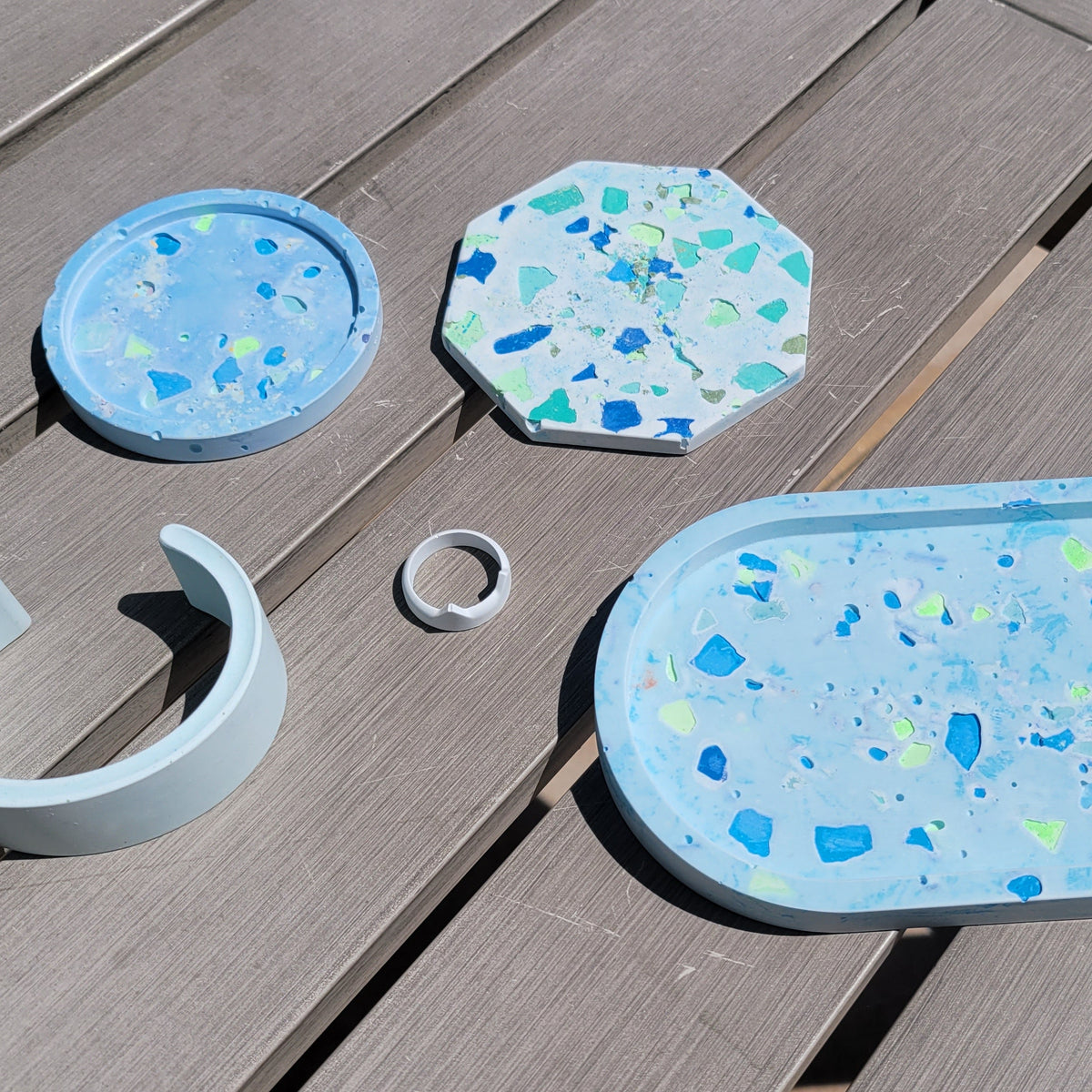Set of decorative trays and coasters with a speckled terrazzo pattern on a wooden surface.