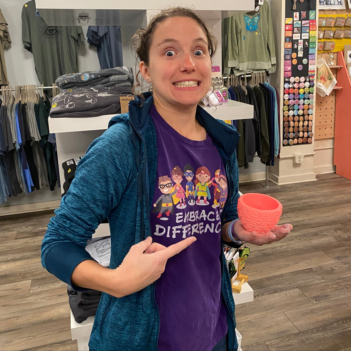 Person in a store holding a pink bowl and pointing.