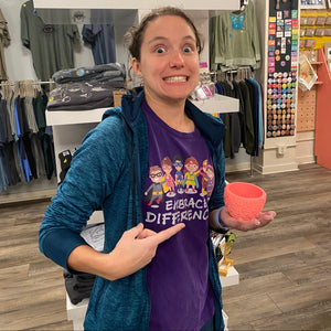 Person in a store holding a pink bowl and pointing.