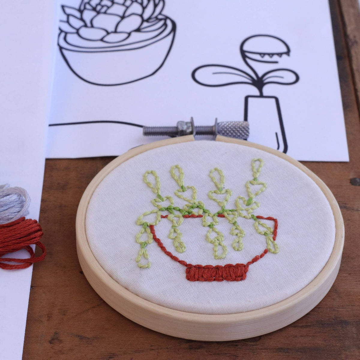 Embroidery hoop with succulent plant design on a wooden surface