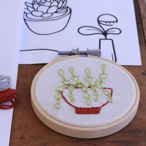 Embroidery hoop with succulent plant design on a wooden surface