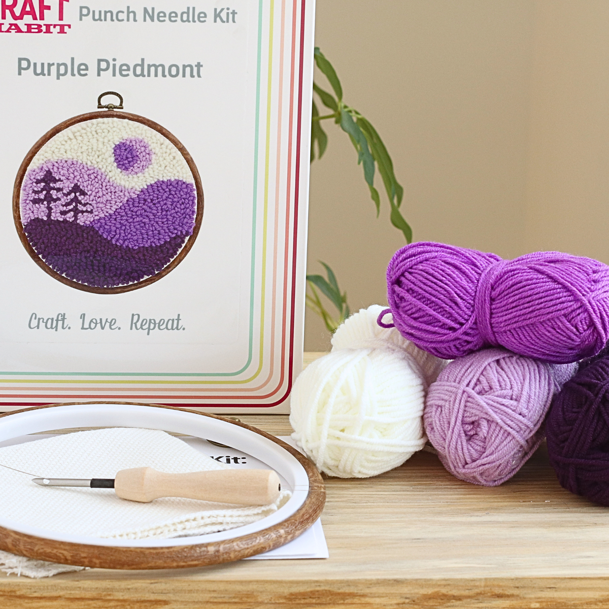 Craft kit with punch needle hoop, yarn, and tools on a wooden surface