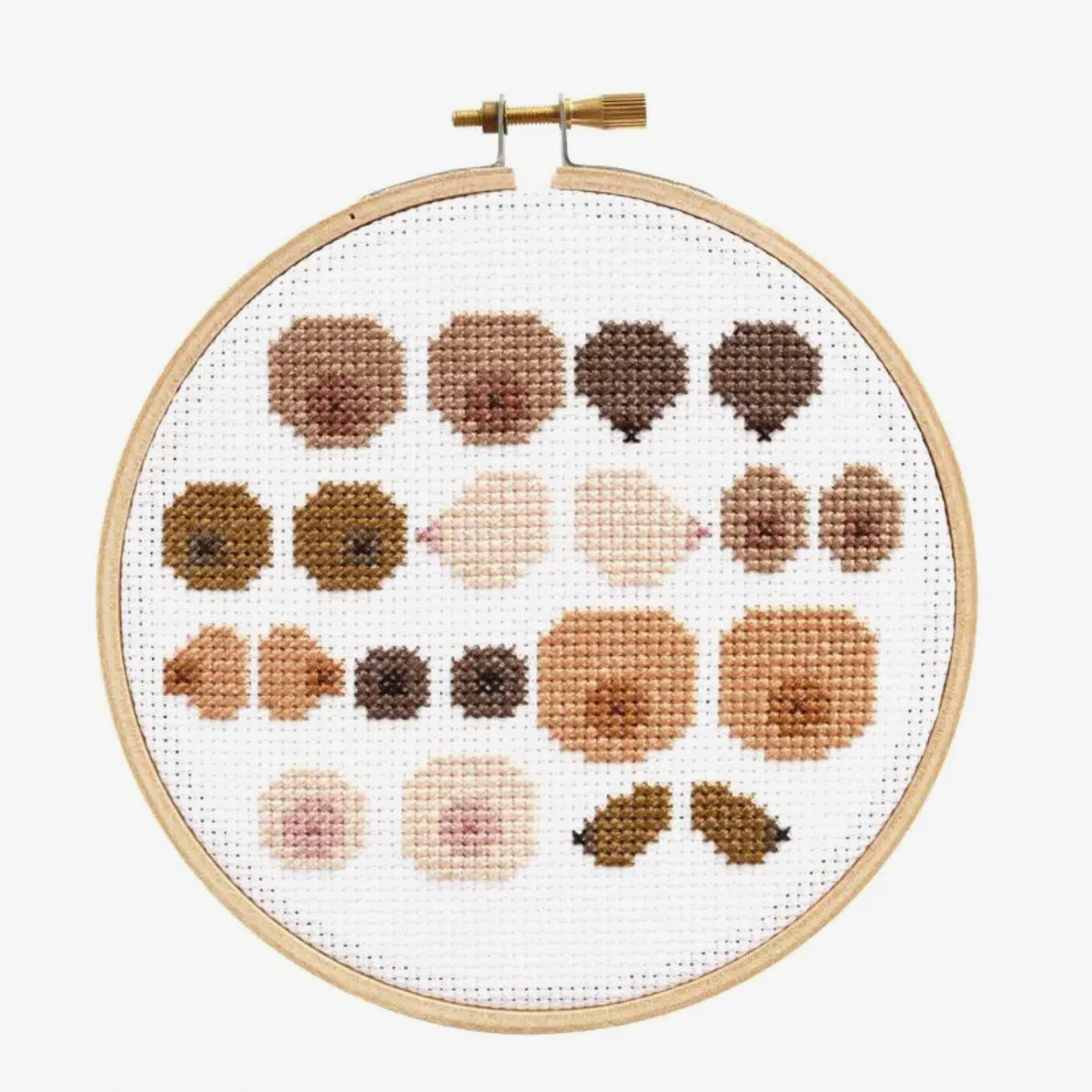 Cross-stitched pattern that includes several different colors and shapes of boobs in an embroidery hoop on a white background. 