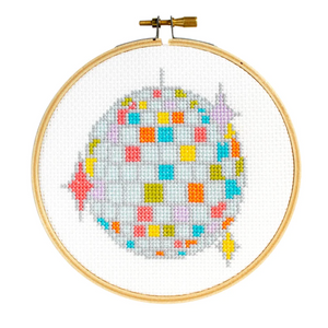 A cross stitch kit in progress depicting a colorful disco ball design within a hoop.