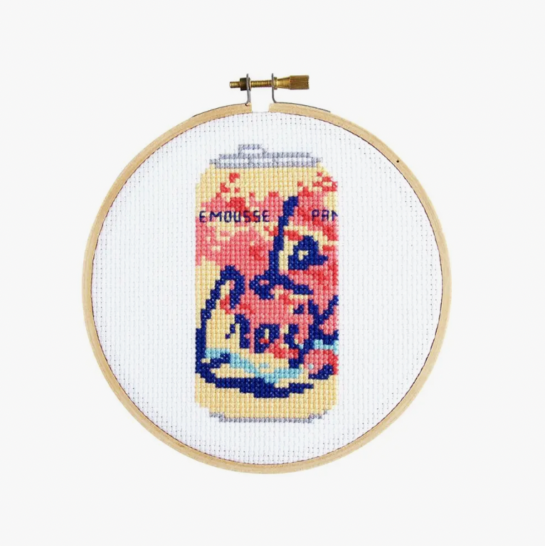 A cross stitch kit depicting a La Croix beverage can in an embroidery hoop.