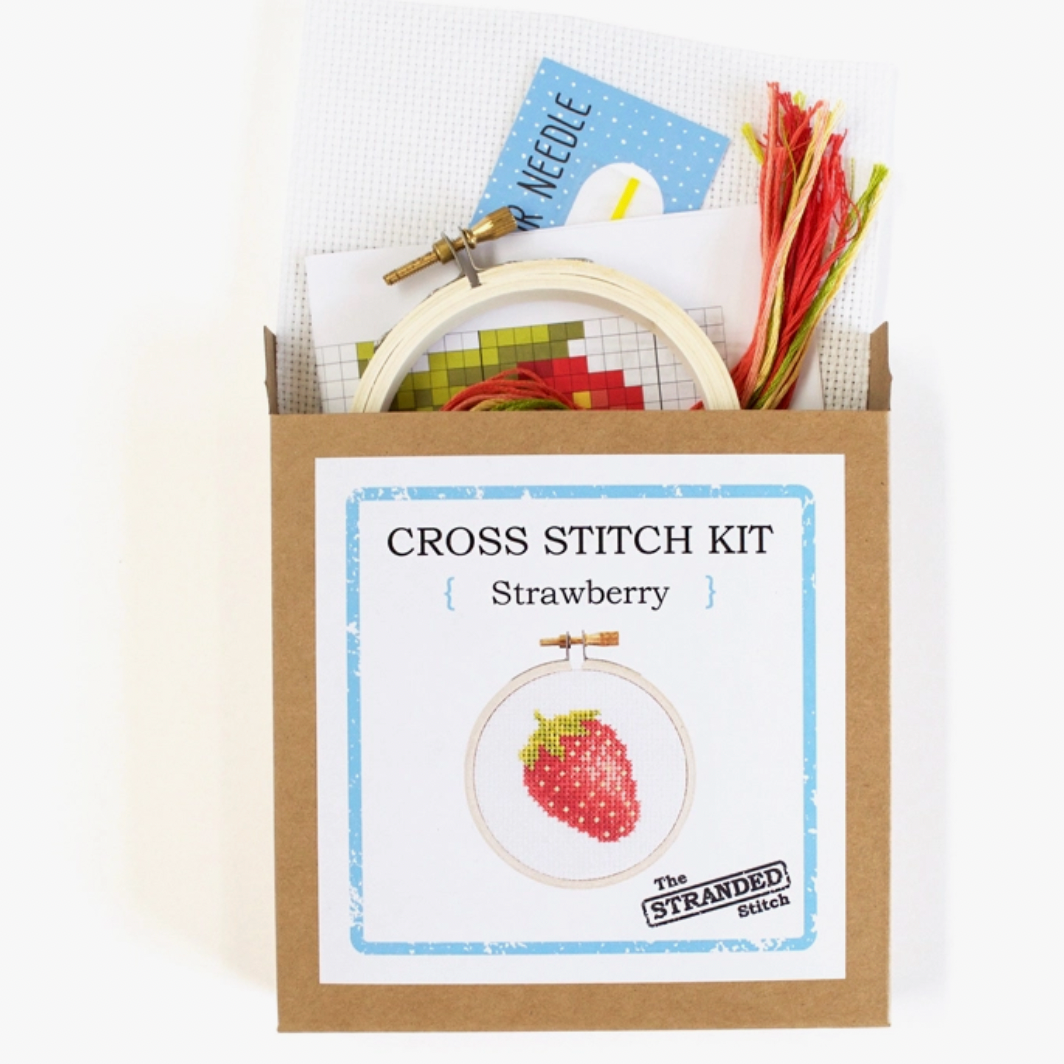 Cross stitch kit with embroidery hoop, thread, and pattern card in a cardboard box. A picture of the comlpleted kit is on the front: A mini strawberry. 