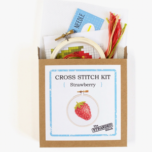 Cross stitch kit with embroidery hoop, thread, and pattern card in a cardboard box. A picture of the comlpleted kit is on the front: A mini strawberry. 