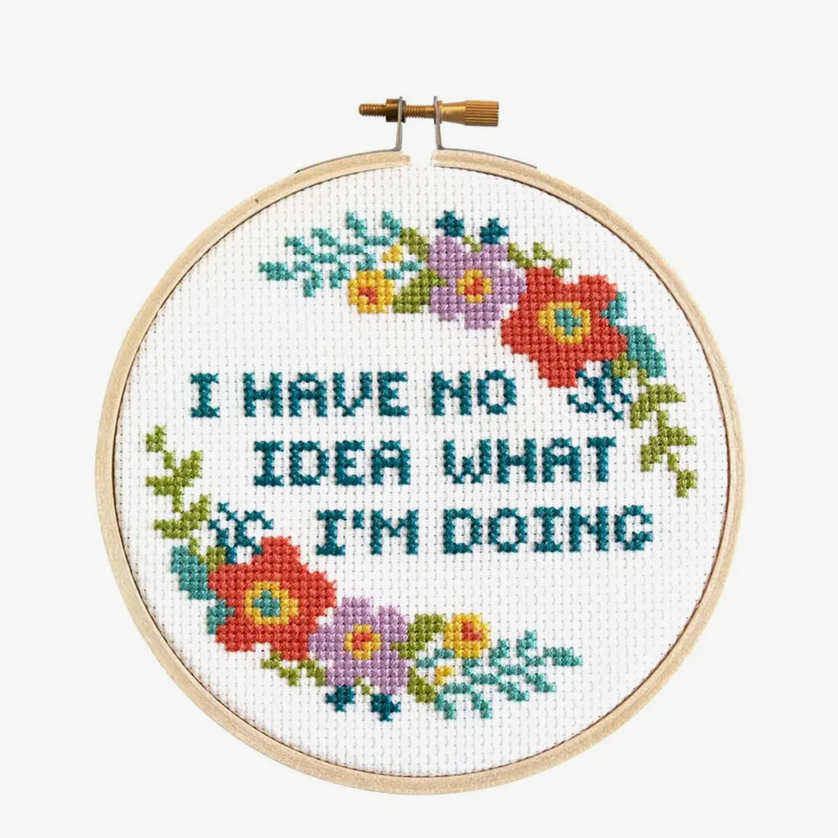 A cross stitch kit with the phrase 'I HAVE NO IDEA WHAT I'M DOING' surrounded by a floral pattern, displayed in an embroidery hoop.