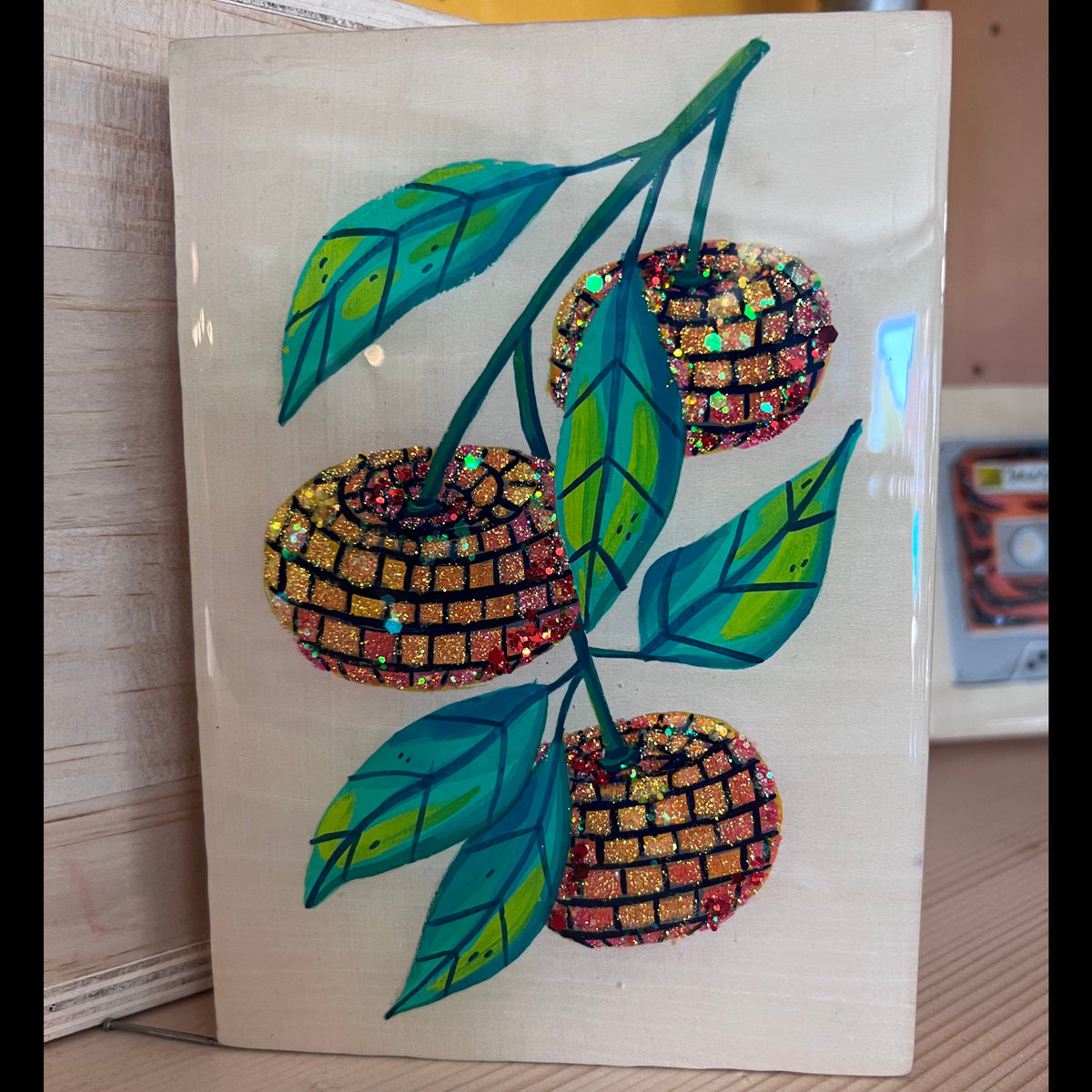 A painting of three oranges as disco balls on a green branch. 