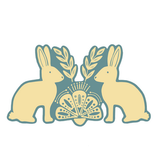 A folk art style sticker with two rabbits looking at each other. There is foliage and a folk are design between them. The rabbits are cream colored and the background is blue. 