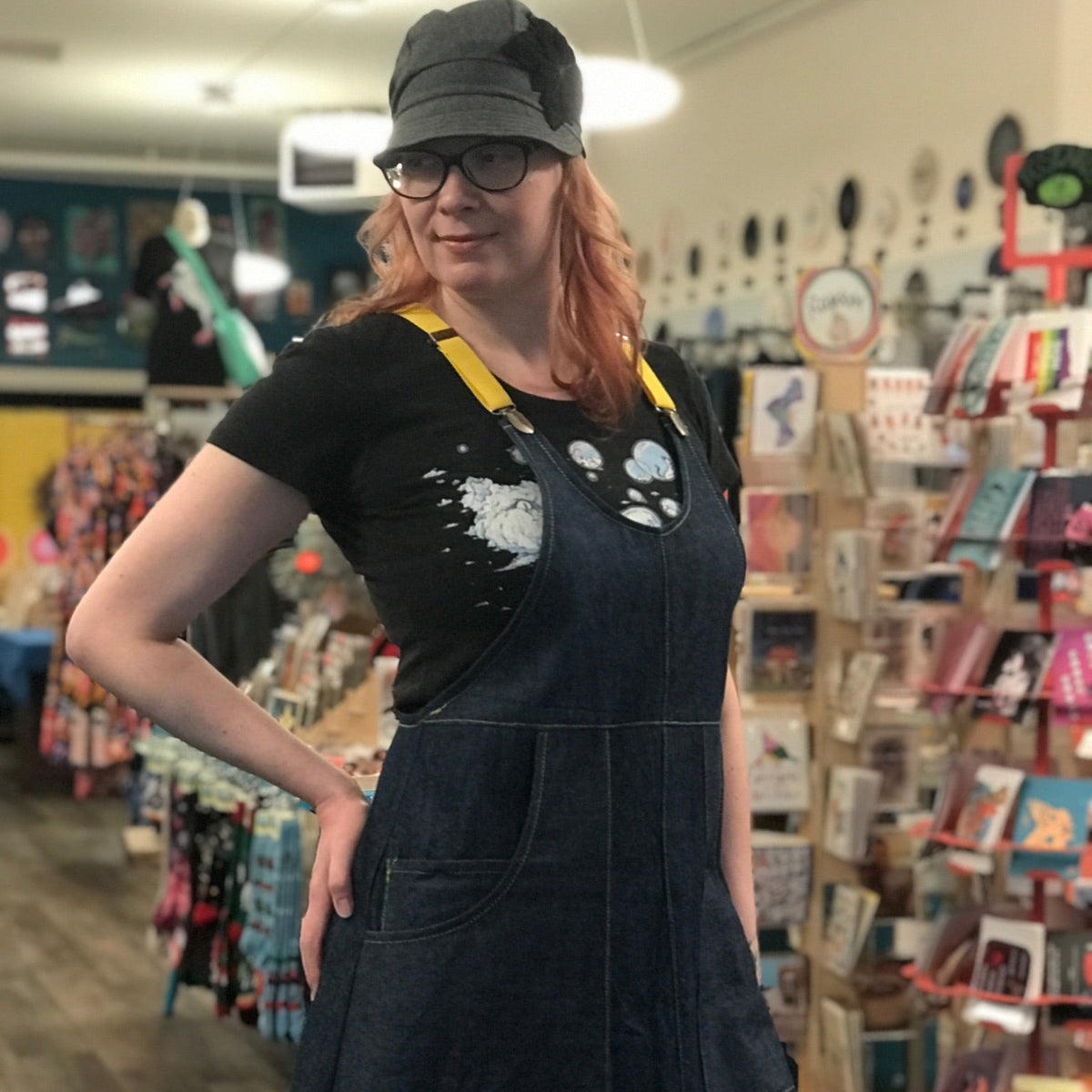 Person wearing a dark blue denim apron and cap in a store setting. 