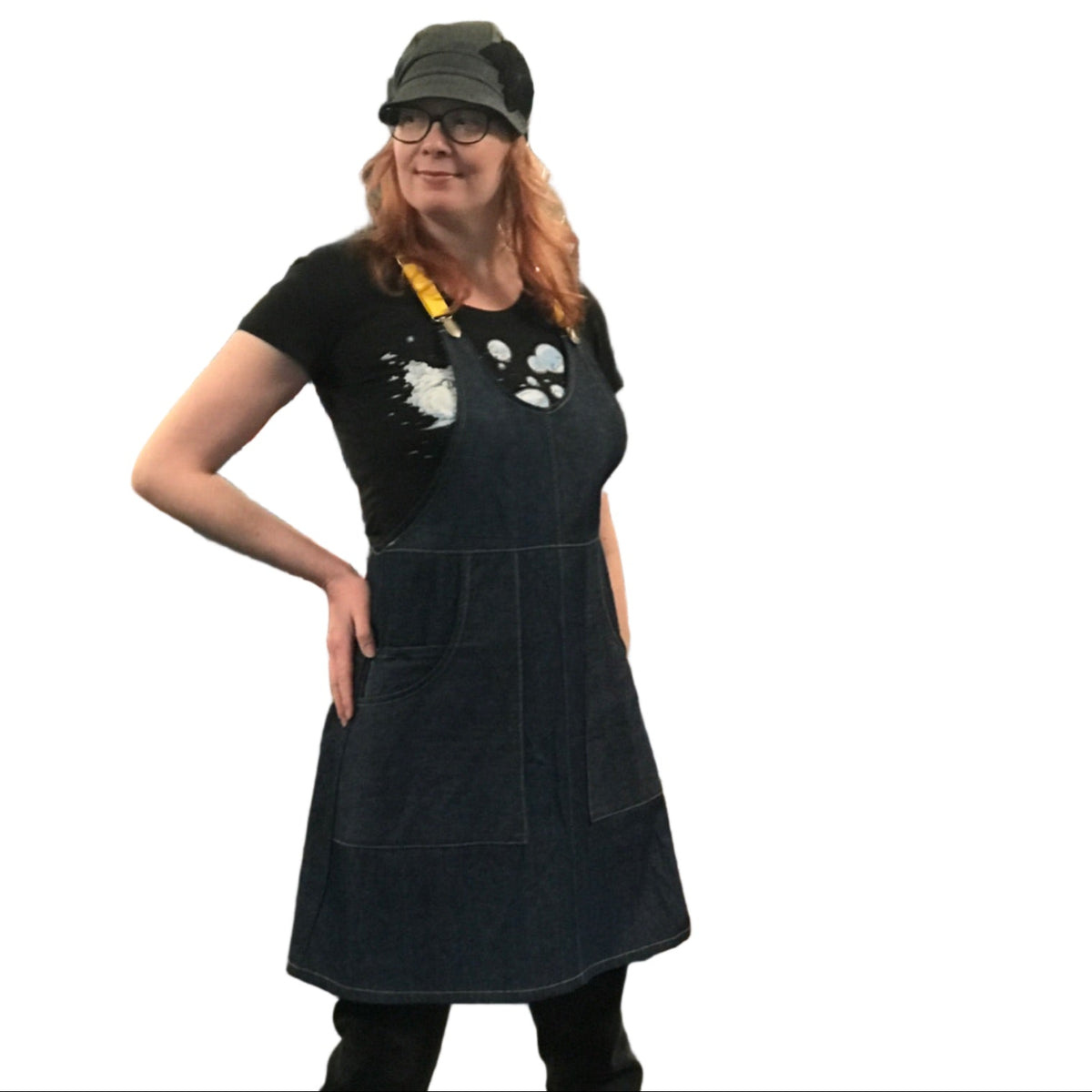 Person wearing a dark denim apron dress in a store setting with various items on display.