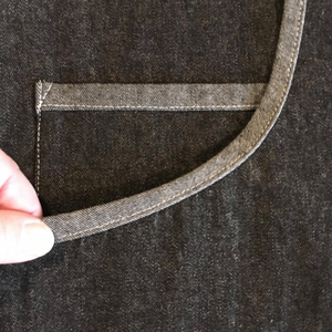 Close-up of a dark gray fabric with a hand holding a piece of it.