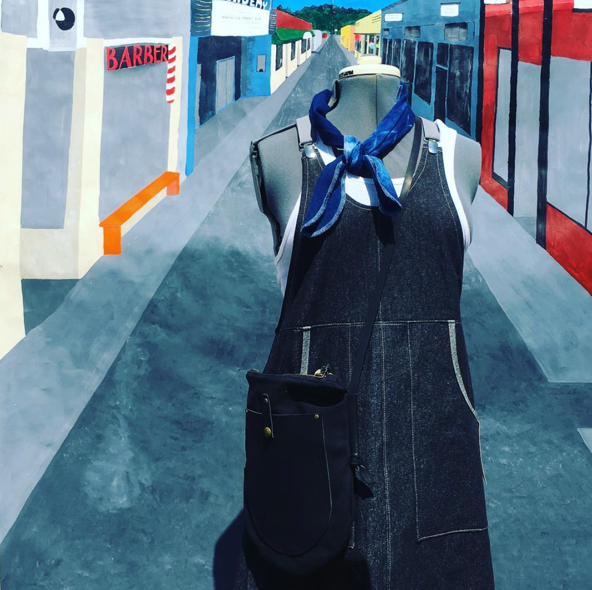 Denim apron with a blue scarf on a stylized city street background