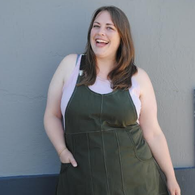 Woman wearing a green apron over a white shirt against a gray wall