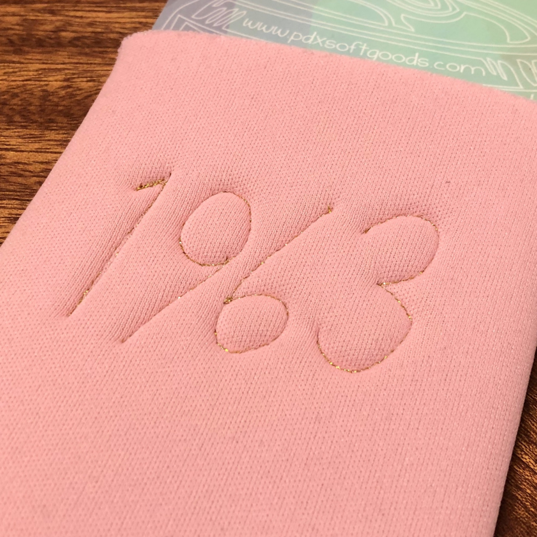 The back of a pink can cooler with 1963 embroidered on the back. 