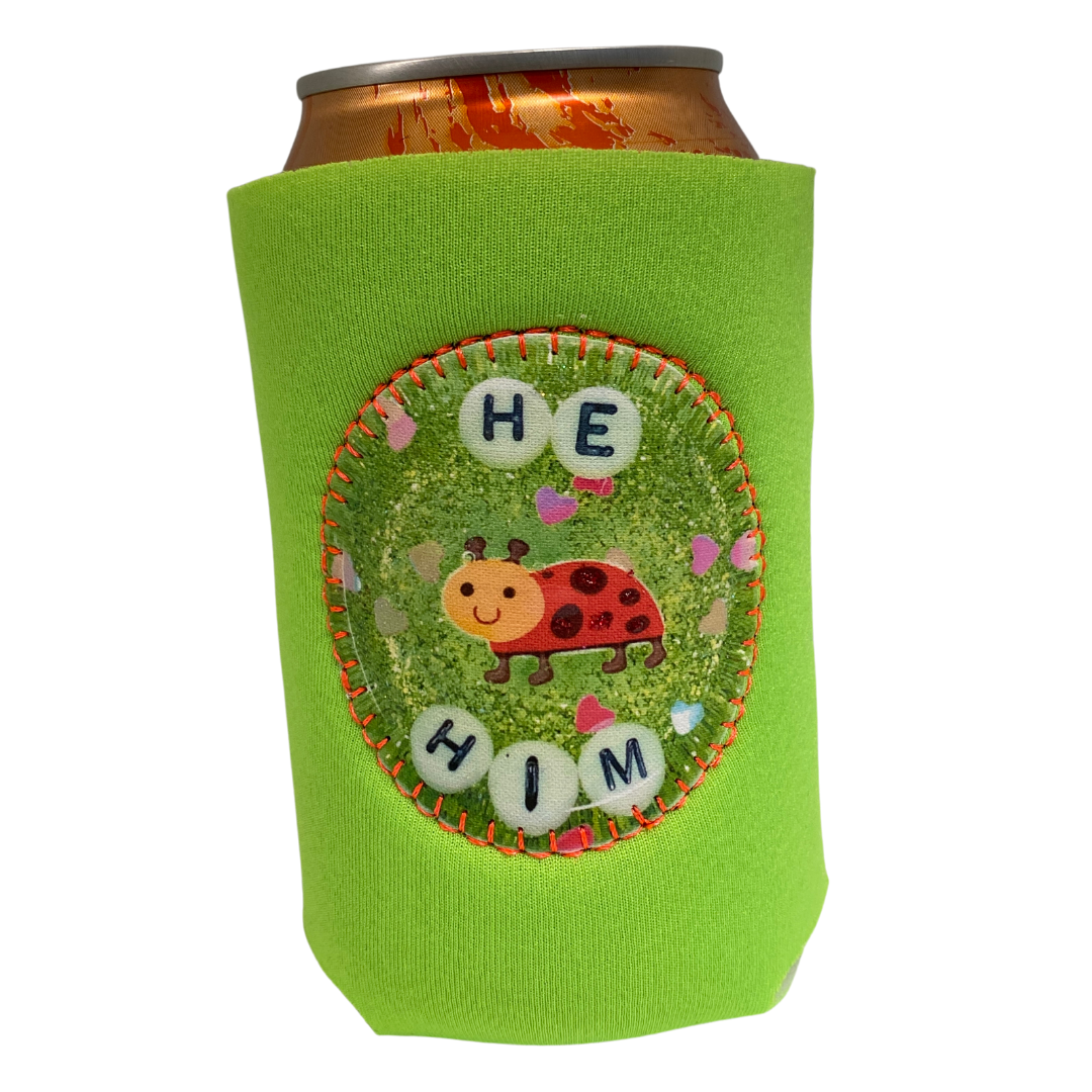 A green can cooler that says "He/Him" on it and has a picture of a lady bug. 