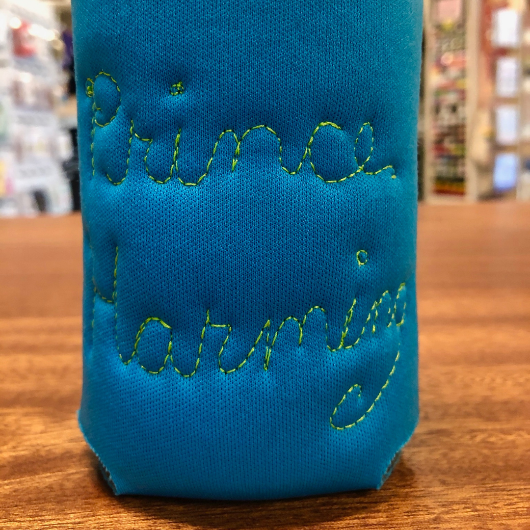 Blue neoprene drink holder that has "Prince Harming" embroidered on the back in cursive. 