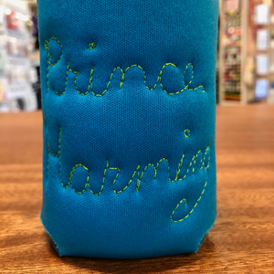 Blue neoprene drink holder that has "Prince Harming" embroidered on the back in cursive. 