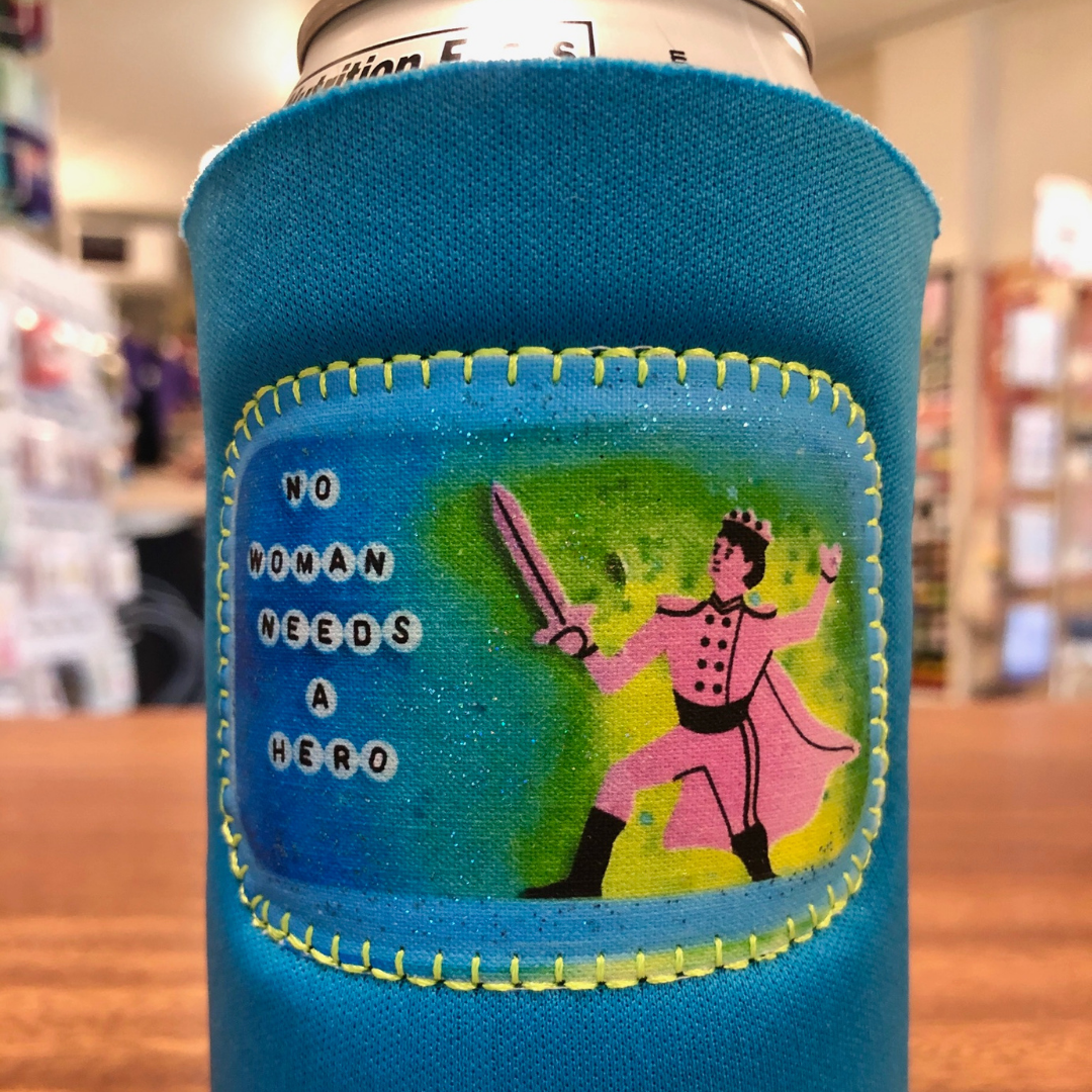Blue neoprene drink holder with a patch that says "No Woman Needs a Hero." 