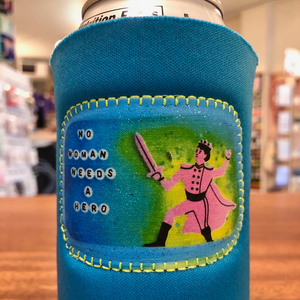 Blue neoprene drink holder with a patch that says "No Woman Needs a Hero." 