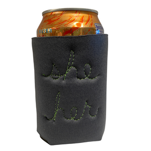 A gray neoprene drink holder with "she/her" embroidered in cursive on the back.
