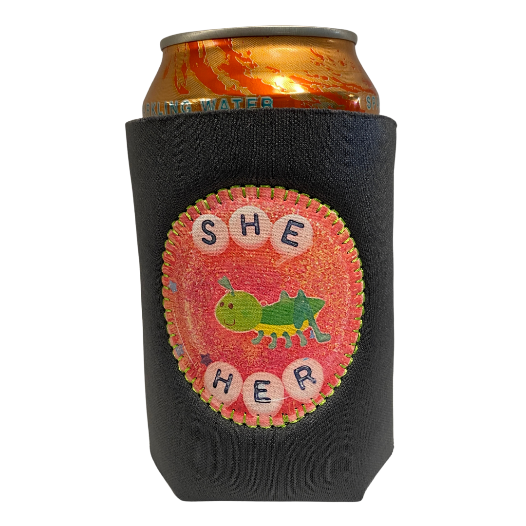 Drink holder with a patch on the front that says "She/Her" 
