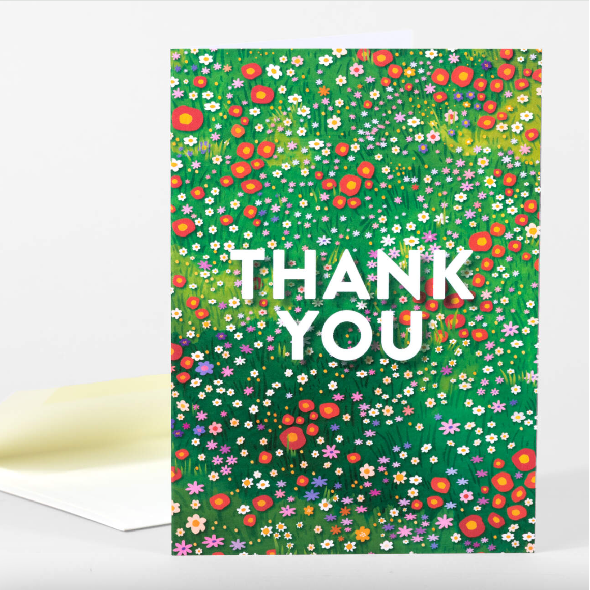 Card with a meadow of multicolored wildflowers and white text on top that says "Thank You"