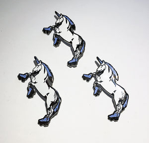 Three identical enamel pins of a rearing white unicorn with a blue mane, tail, and hooves, outlined in black, arranged on a plain white background.