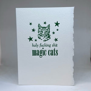Letterpress greeting card with a cat illustration and text that says "holy fucking shit magic cats" on a white background. 