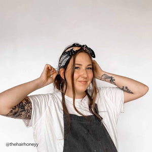Person wearing a patterned bandana as a headband against a white background. 