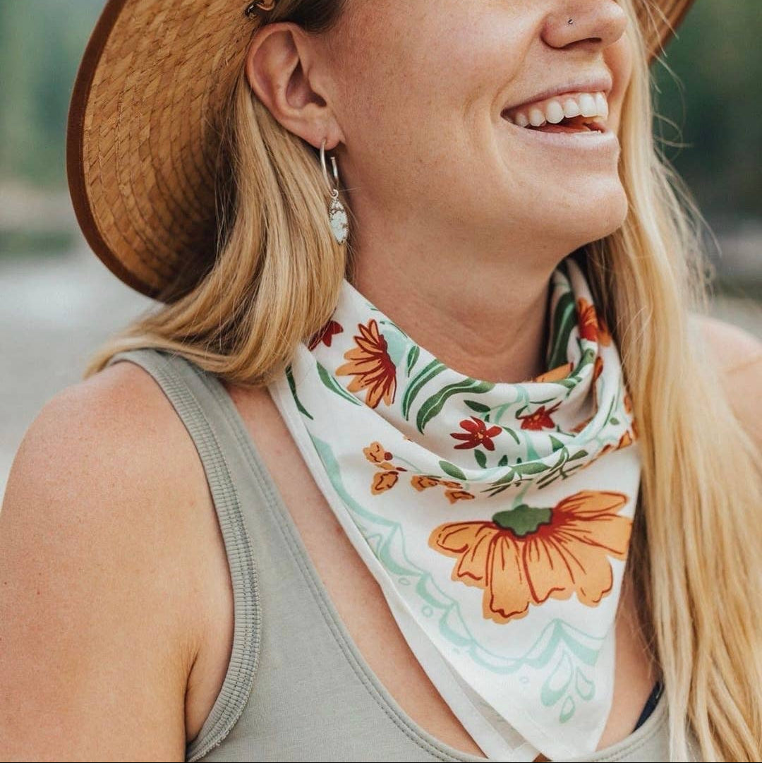 Person modeling a floral patterned bandana and wearing a straw hat. 