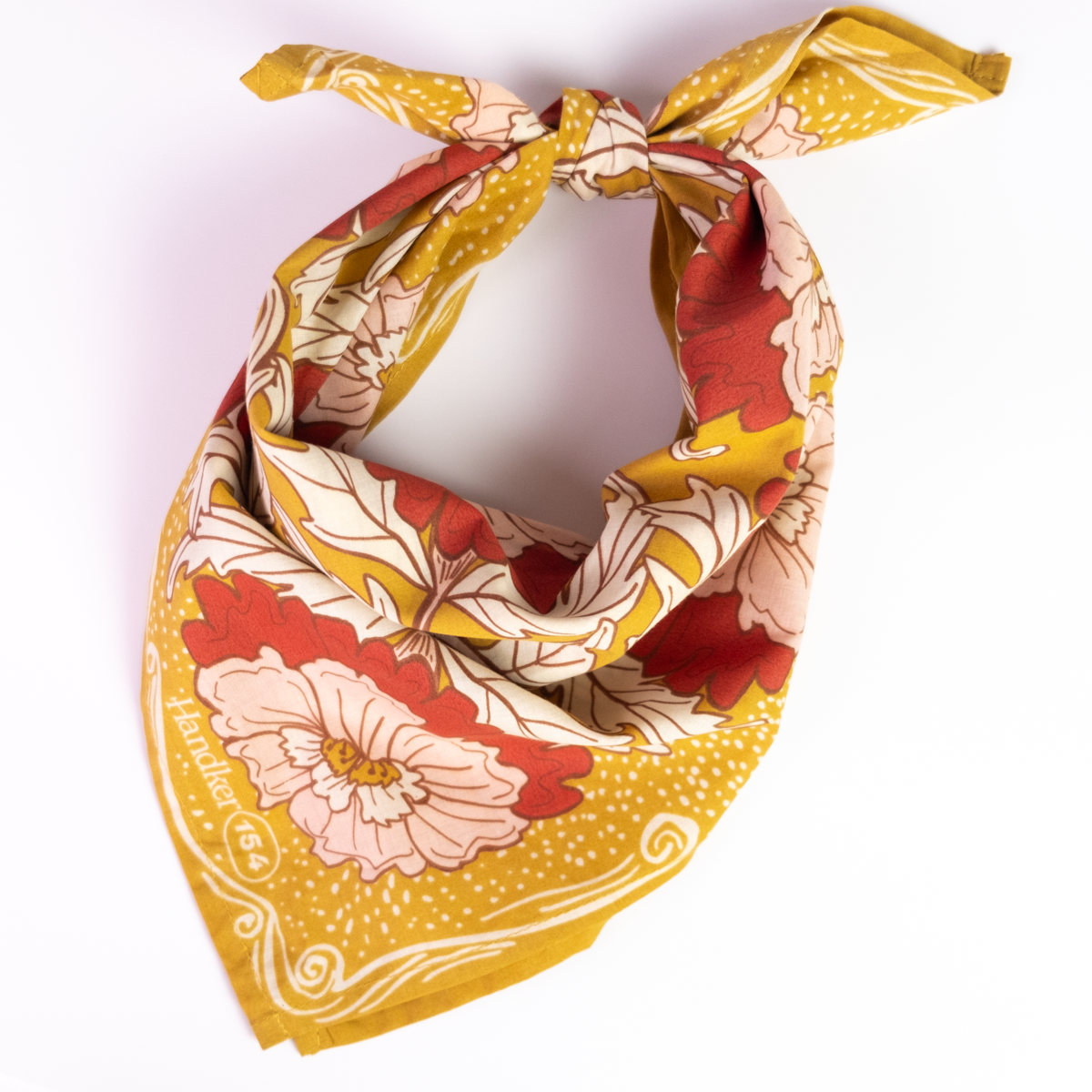 A yellow floral patterned bandana tied into a scarf, against a white background. 